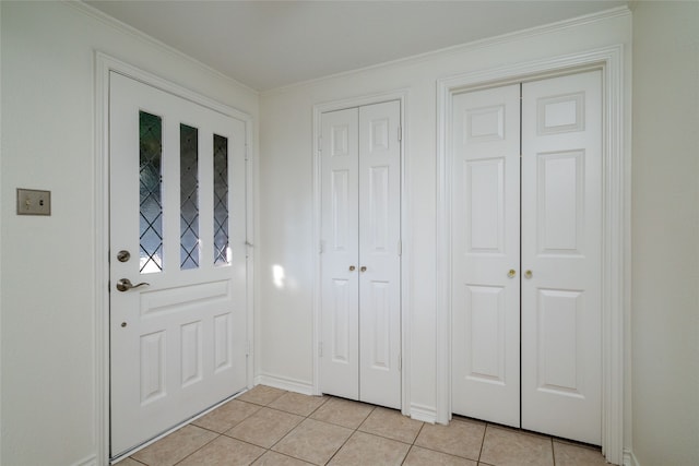 entryway with ornamental molding and light tile patterned floors