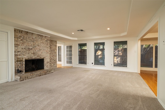 unfurnished living room with carpet floors, a fireplace, and a raised ceiling