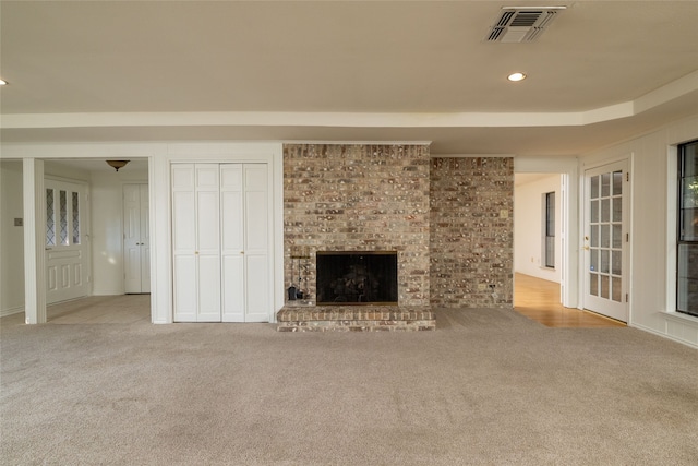 unfurnished living room with a brick fireplace and light colored carpet