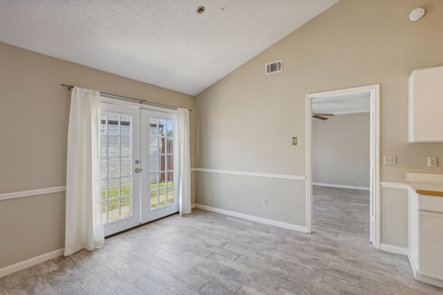 interior space featuring light wood-type flooring, french doors, a textured ceiling, ceiling fan, and lofted ceiling