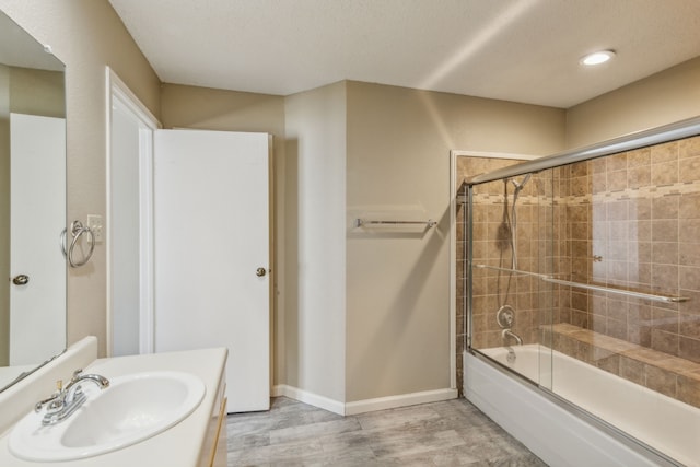 bathroom with vanity, a textured ceiling, bath / shower combo with glass door, and hardwood / wood-style flooring