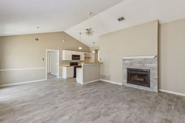 unfurnished living room featuring light hardwood / wood-style floors, ceiling fan, a fireplace, and vaulted ceiling