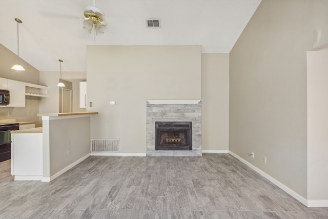 unfurnished living room featuring a stone fireplace, ceiling fan, light wood-type flooring, and vaulted ceiling