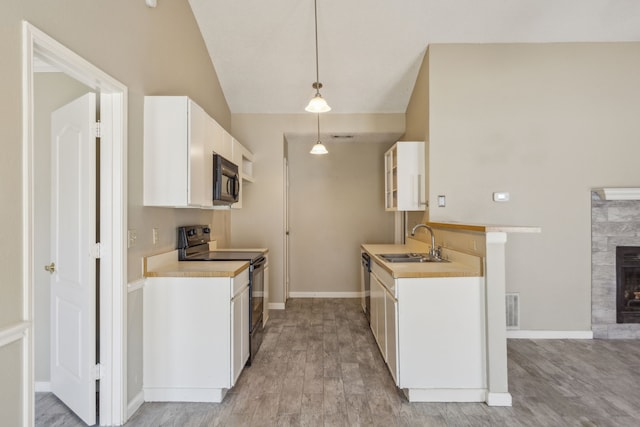 kitchen featuring white cabinetry, light wood-type flooring, black appliances, sink, and decorative light fixtures