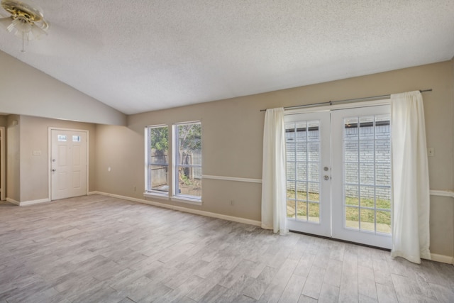 interior space featuring french doors, a textured ceiling, vaulted ceiling, and light wood-type flooring