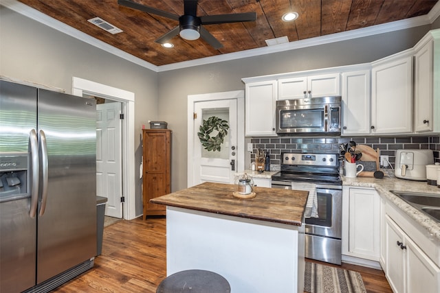 kitchen with appliances with stainless steel finishes, white cabinets, butcher block counters, and wood-type flooring