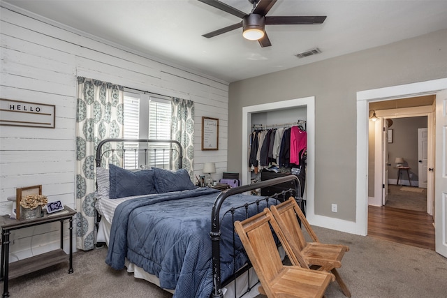 bedroom featuring a closet, ceiling fan, wood walls, and carpet flooring