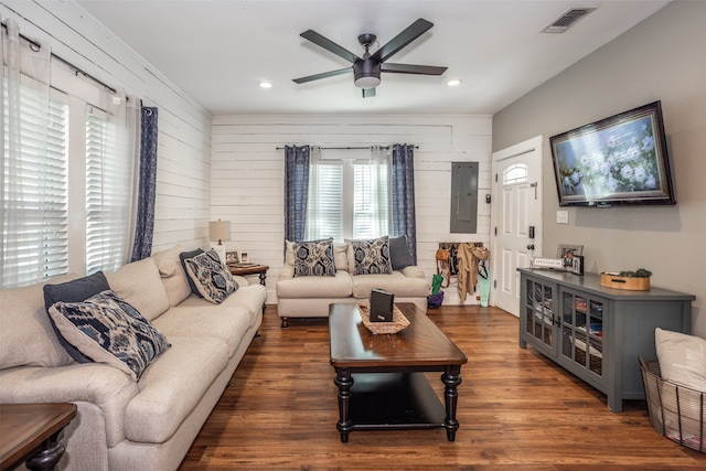 living room featuring wood walls, dark wood-type flooring, electric panel, and ceiling fan