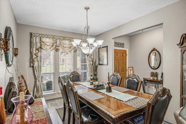 dining space featuring light hardwood / wood-style floors, a textured ceiling, and a notable chandelier