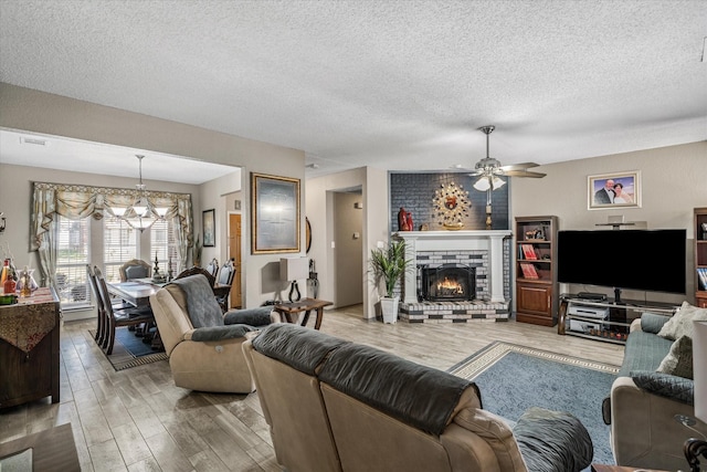 living room with a fireplace, hardwood / wood-style floors, ceiling fan with notable chandelier, and a textured ceiling