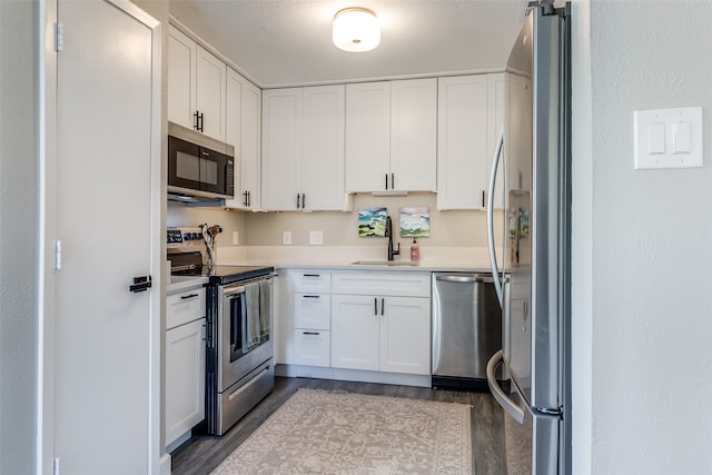 kitchen with sink, appliances with stainless steel finishes, dark hardwood / wood-style floors, and white cabinets