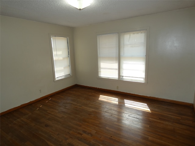 spare room featuring a textured ceiling and dark hardwood / wood-style floors