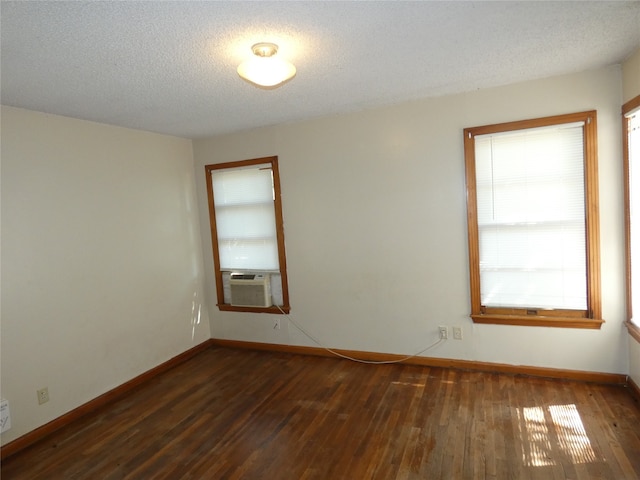 spare room with a textured ceiling, dark hardwood / wood-style flooring, and cooling unit