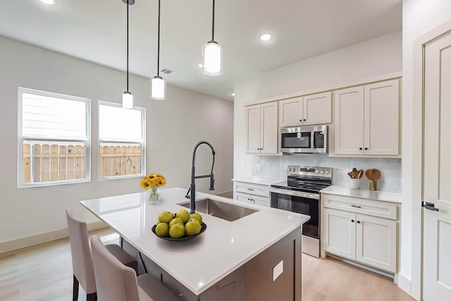 kitchen with pendant lighting, sink, white cabinets, and stainless steel appliances