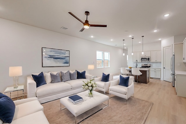 living room with sink, ceiling fan, and light hardwood / wood-style flooring