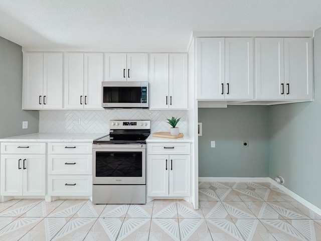 kitchen featuring decorative backsplash, white cabinetry, light tile patterned floors, and appliances with stainless steel finishes