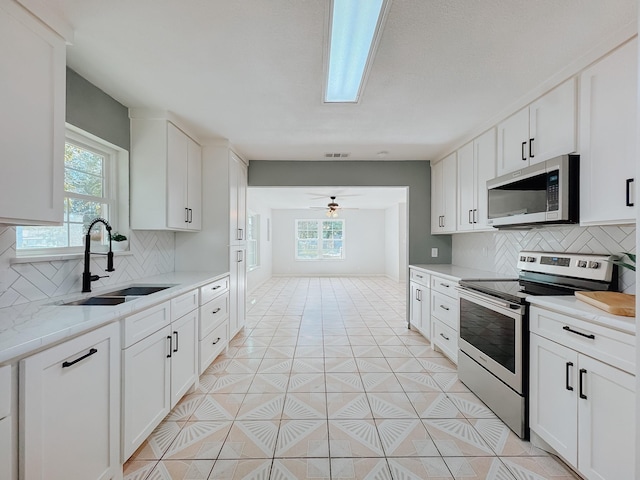 kitchen featuring decorative backsplash, sink, white cabinetry, and stainless steel appliances