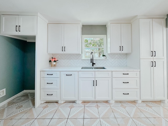 kitchen featuring white cabinets, backsplash, and sink