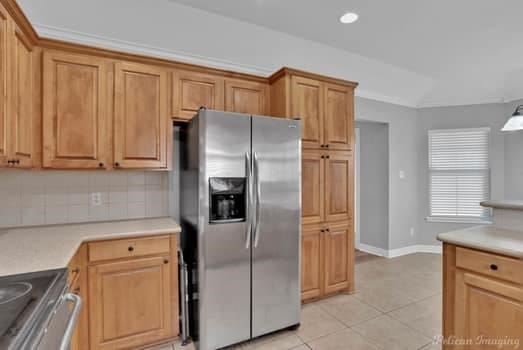 kitchen with decorative backsplash, black range, light tile patterned floors, and stainless steel fridge with ice dispenser