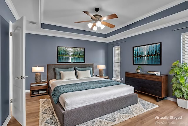 bedroom with crown molding, wood-type flooring, a raised ceiling, and ceiling fan