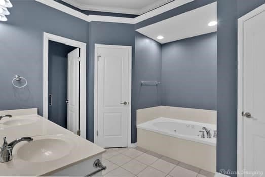 bathroom featuring vanity, ornamental molding, a tub to relax in, and tile patterned flooring