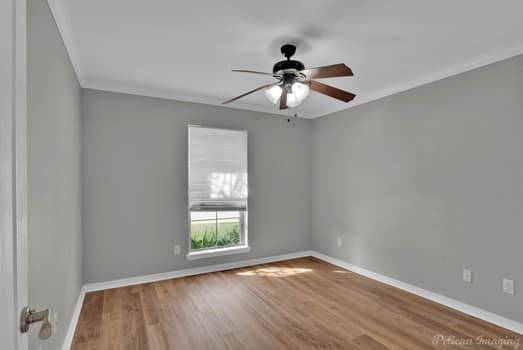 empty room with ornamental molding, hardwood / wood-style floors, and ceiling fan