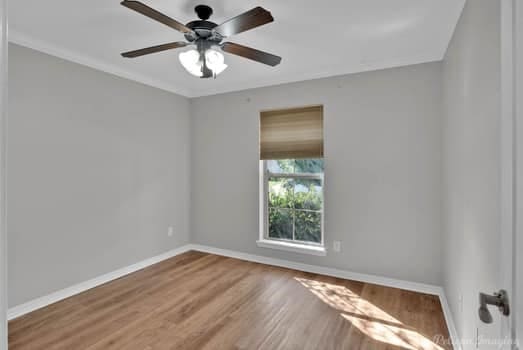 empty room with ornamental molding, hardwood / wood-style flooring, and ceiling fan