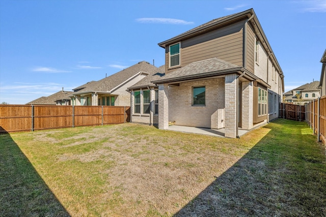 rear view of house with a yard, brick siding, a patio area, and a fenced backyard