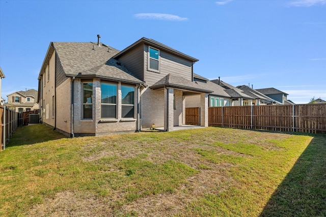 rear view of property featuring brick siding, a yard, central air condition unit, a shingled roof, and a fenced backyard