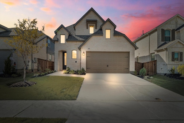 french country style house featuring roof with shingles, brick siding, fence, a garage, and driveway