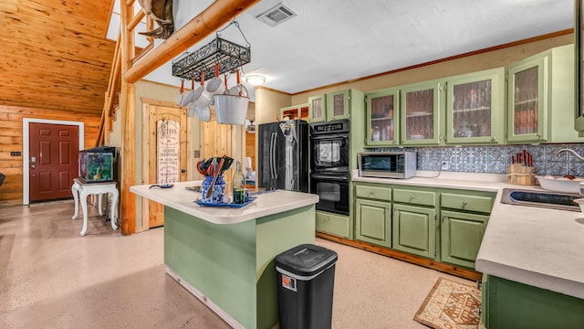 kitchen featuring wooden walls, green cabinets, backsplash, sink, and black appliances