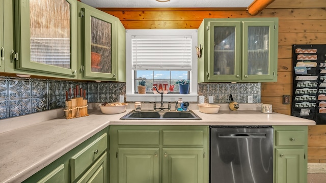 kitchen with sink, wooden walls, green cabinetry, and dishwasher