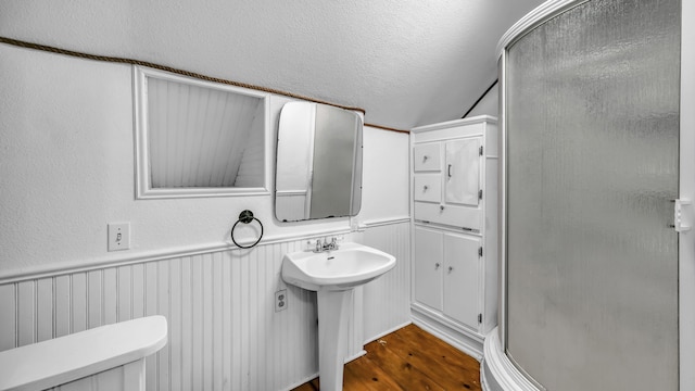 bathroom featuring hardwood / wood-style floors, a textured ceiling, walk in shower, toilet, and sink