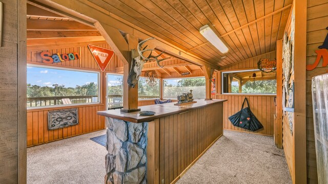 bar with wood ceiling, wood walls, light colored carpet, and vaulted ceiling