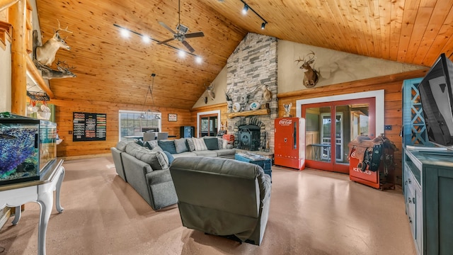 living room with wooden walls, a stone fireplace, high vaulted ceiling, and wooden ceiling