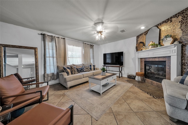 tiled living room with ceiling fan and a fireplace