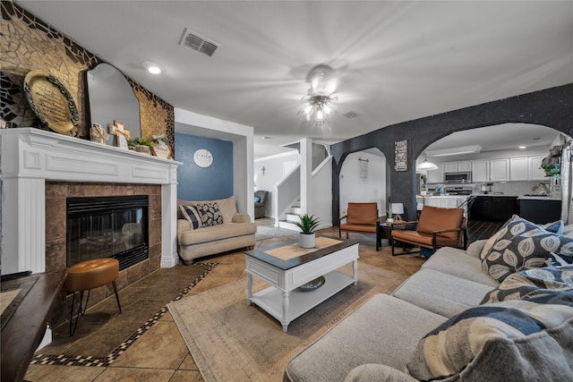 living room featuring ceiling fan, a fireplace, and light tile patterned floors