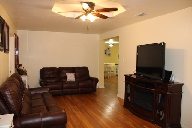 living room featuring dark wood-type flooring and ceiling fan