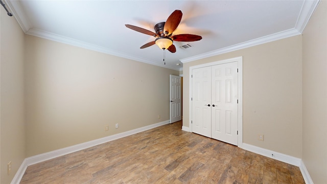 unfurnished bedroom with hardwood / wood-style floors, crown molding, a closet, and ceiling fan