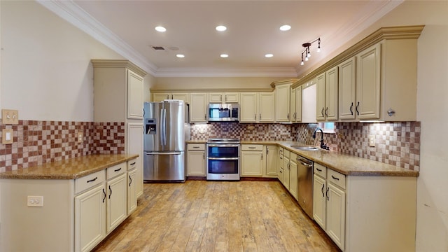 kitchen with decorative backsplash, cream cabinets, appliances with stainless steel finishes, light wood-type flooring, and sink