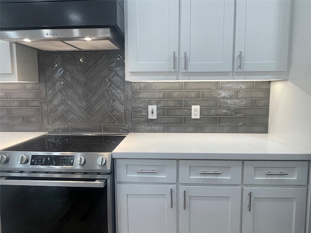 kitchen featuring stainless steel electric range, backsplash, extractor fan, white cabinetry, and light stone countertops