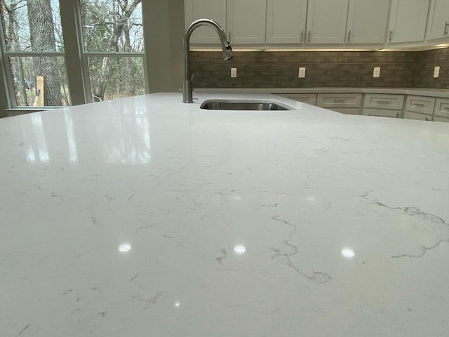 interior space featuring light stone counters, decorative backsplash, and sink