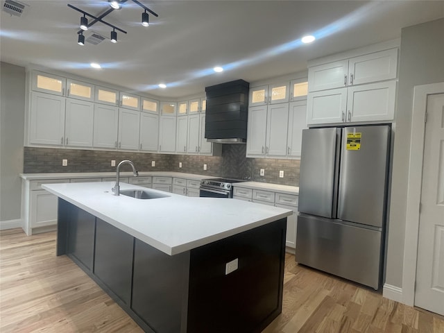 kitchen featuring an island with sink, custom range hood, stainless steel appliances, and white cabinets