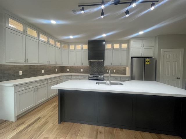 kitchen with custom exhaust hood, a center island with sink, stainless steel appliances, and sink