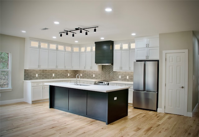 kitchen featuring an island with sink, stainless steel appliances, sink, custom exhaust hood, and white cabinetry