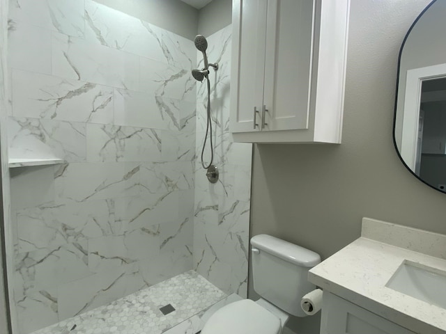 bathroom with vanity, toilet, and tiled shower