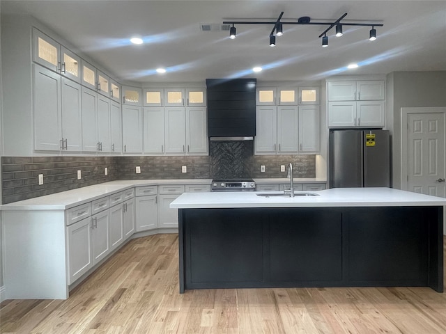 kitchen with sink, an island with sink, stainless steel appliances, custom exhaust hood, and white cabinets