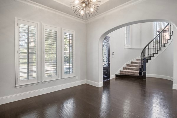 entryway featuring ornamental molding, a chandelier, plenty of natural light, and dark hardwood / wood-style floors