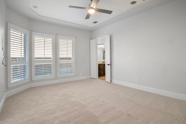 unfurnished bedroom with light carpet, ensuite bathroom, and ceiling fan