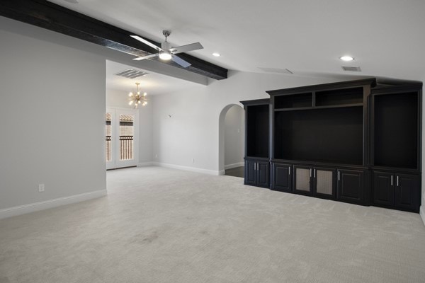 unfurnished living room featuring light colored carpet, vaulted ceiling with beams, and ceiling fan with notable chandelier